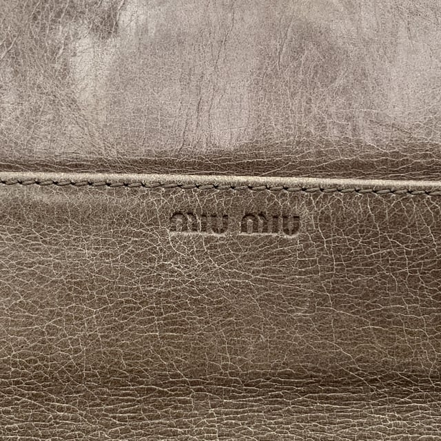 VINTAGE, RRP WIE NEU  
Elegant und mit einem Hauch von Kante, ist dieses Miu Miu Continental Wallet ein verfeinerter Klassiker, eingehüllt in taupefarbenes Matelassé-Leder mit einem subtilen, abgenutzten Effekt, der genau den richtigen Charakter zu seiner eleganten Silhouette hinzufügt. Das ikonische goldene MIU MIU-Logo glänzt auf dem Verschluss, der mit einem dezenten Knopf gesichert ist. Öffnen Sie es, um ein durchdacht gestaltetes Inneres zu enthüllen: 12 Kreditkartenfächer, zwei geräumige Fächer, ein Münzfach mit Reißverschluss und eine seitliche offene Sektion, die ordentlich unter dem Verschluss verborgen ist. Innen ist 'MIU MIU' in das Leder eingeprägt, mit einer Seriennummer, die als leise Markierung der Authentizität dient. Unaufdringlich und endlos schick, ist dieses Stück mehr als nur eine Geldbörse – es ist ein kleines Stück von Miu Mius verspielter Eleganz, das dazu gemacht ist, getragen und geschätzt zu werden.  
Zustandsbewertung: B - SEHR GUTER ZUSTAND  
Zustandsdetails: Sanft gebraucht. Einige leichte Kratzer auf dem Leder aufgrund normalen Gebrauchs. Miu Miu-Box enthalten. Bitte überprüfen Sie die Fotos sorgfältig und fragen Sie, wenn Sie mehr Details wissen möchten oder Zweifel haben.  
Maße (cm): Höhe: 10,2 Länge: 19,1  
Box?: Ja  
Maße: Länge: 191 mm Höhe: 102 mm