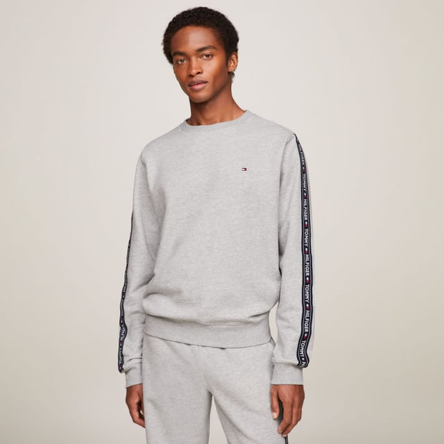 Men's Tommy Hilfiger Logo Tape Lounge Sweatshirt in Grey Ribbed crewneck.Ribbed cuffs and hem.TH logo stripes on the sleeves.Tommy Hilfiger flag embroidery on the chest.Regular fit.