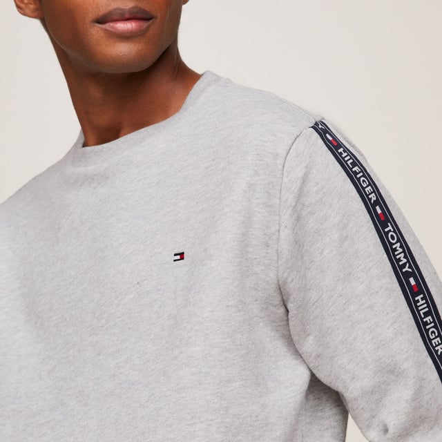 Men's Tommy Hilfiger Logo Tape Lounge Sweatshirt in Grey Ribbed crewneck.Ribbed cuffs and hem.TH logo stripes on the sleeves.Tommy Hilfiger flag embroidery on the chest.Regular fit.