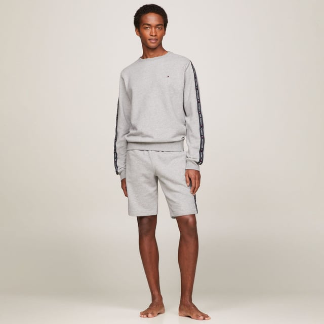 Men's Tommy Hilfiger Logo Tape Lounge Sweatshirt in Grey Ribbed crewneck.Ribbed cuffs and hem.TH logo stripes on the sleeves.Tommy Hilfiger flag embroidery on the chest.Regular fit.