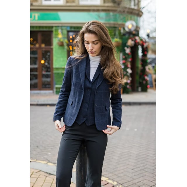 Dieser elegante und zeitlose Damenblazer ist in einem luxuriösen marineblauen Tweed-Karomuster gefertigt. Gefertigt aus einer hochwertigen Wollmischung bietet der Blazer die perfekte Balance aus Komfort, Strapazierfähigkeit und elegantem Stil – ideal für geschäftliche und legere Anlässe. Der vollständig gefütterte Blazer verfügt über eine Zwei-Knopf-Front, zwei Pattentaschen, einen Schlitz hinten und markante Ellbogenflicken, die ihm einen Hauch von traditionellem Charme verleihen. Elegantes Design: Klassisches marineblaues Karomuster für einen eleganten und vielseitigen Look. Blazerdetails: Zwei-Knopf-Verschluss, Ellbogenflicken, Pattentaschen, Schlitz hinten und durchgehendes Futter. Hochwertiges Material: Hochwertige Mischung aus 50 % Wolle, 35 % Polyester und 15 % Viskose. Elegant-legere Vielseitigkeit: Ideal für Business, Büro oder den gehobenen Alltagslook.