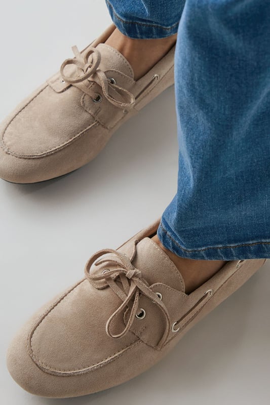 Faux suede boat shoes with classic moccasin-inspired design
        Traditional lace detail with neat bow fastening for adjustable fit
        Comfortable flat heel measuring between 0-2cm for all-day wear
        Soft rounded toe shape offering ample room for movement
        Subtle stitching detail around the upper for added visual interest
    
    The Faith Nico boat shoes blend timeless nautical charm with everyday practicality. These versatile flats feature the classic boat shoe silhouette reimagined in soft faux suede for a contemporary twist on a wardrobe staple. Perfect for casual weekend outings, pair them with wide-leg jeans as shown for an effortlessly chic look, or style with cropped trousers and a crisp white shirt for smart-casual occasions. The neutral tone makes these shoes incredibly adaptable for your wardrobe, while the comfortable flat design ensures they're suitable for long days of wear. Ideal for family gatherings, shopping trips or casual lunches, these boat shoes offer the perfect balance of comfort and style without compromising on either. Their understated design makes them a reliable choice for transitional weather, working beautifully with both summer dresses and autumn layering pieces.