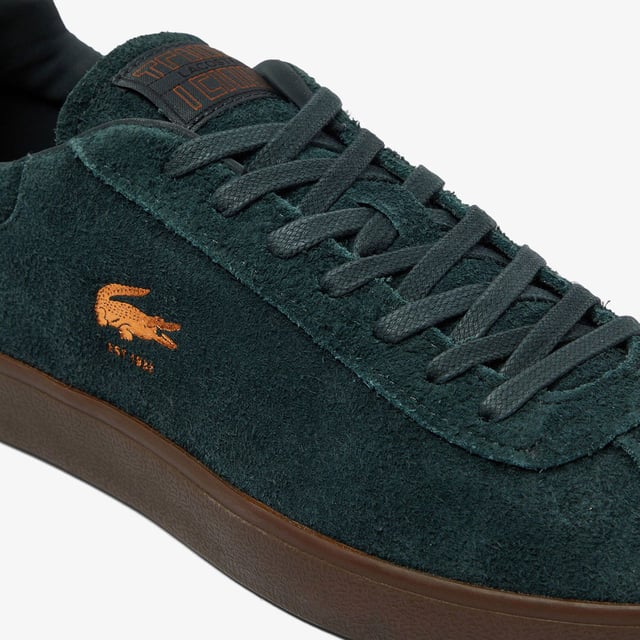 Men's Lacoste Baseshot Suede Trainers in Green Men's Baseshot Suede Sneakers Premium suede upper Padded collar for increased comfort and support Vintage tennis label on tongue Supple high-grip rubber outsole Debossed retro crocodile on front panel
