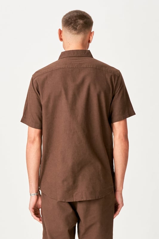 Dieses kurzärmelige Leinenhemd in Dunkelbraun ist die perfekte Wahl für den stilvollen Mann. Mit seinem leichten und atmungsaktiven Material, bestehend aus 70 % Baumwolle und 30 % Leinen, sorgt es auch an den heißesten Tagen für höchsten Tragekomfort. Dieses Hemd eignet sich sowohl für formelle als auch für ungezwungene Anlässe und vereint Eleganz mit Funktionalität. Der zeitlose Kaffeeton ergänzt jede Garderobe und ist somit unverzichtbar für den modernen Mann. Tauchen Sie ein in die Sommertrends mit diesem vielseitigen Hemd, das beeindrucken und einen klassischen Stil liefern soll.