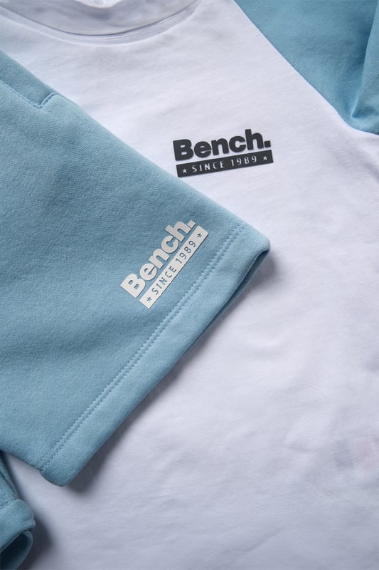 Upgrade everyday style with this easygoing three-piece set from Bench, featuring a classic cotton T-shirt, soft sweat shorts, and a coordinating cotton twill hat. The brushed sweat fabric offers a comfy feel, while ribbed trims and a flat woven drawcord add function and fit. Designed for casual versatility, this outfit set delivers effortless comfort from top to toe.