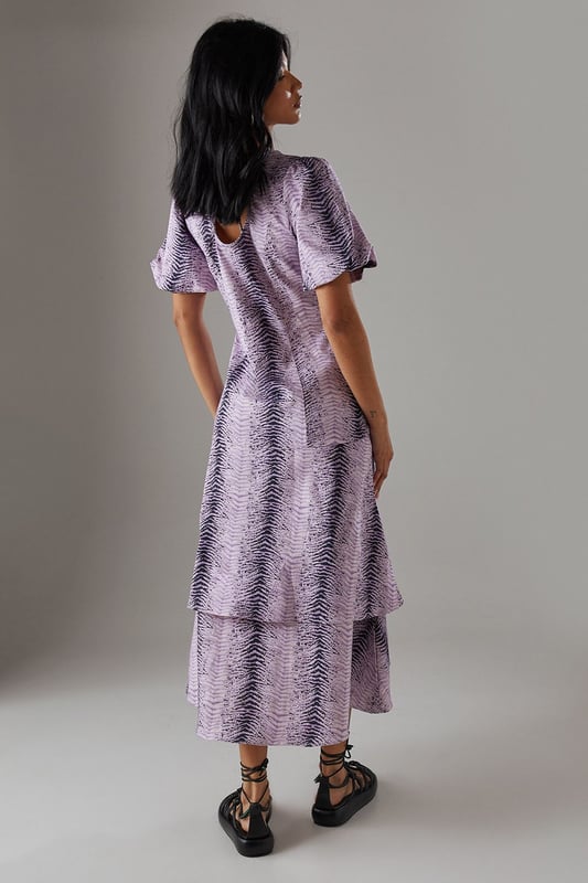 Striking animal print twill fabric with textured finish
        Feminine puff sleeves add volume and contemporary flair
        Tiered ruffle hem creates movement and dimension
        Midi length offers versatile styling options
        Relaxed silhouette with round neckline for effortless comfort
    
    Make a statement in this bold animal print midi dress from Warehouse. The distinctive puff sleeves create a contemporary silhouette while the playful ruffle hem adds movement and feminine charm. The twill fabric provides structure whilst maintaining a comfortable feel for all-day wear. Style with chunky flat sandals as shown for a casual daytime look, or transform for evening gatherings with ankle boots and statement earrings. Perfect for family gatherings or weekend brunches, this dress offers versatility without compromising on style. Layer with a denim jacket when the temperature drops or wear alone to showcase the eye-catching print. The midi length works beautifully with both flats and low heels, making this a truly adaptable addition to your wardrobe.