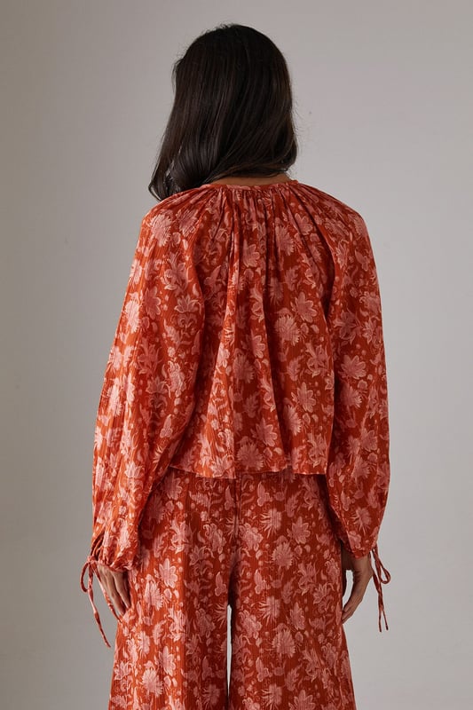 Cheesecloth fabric with delicate floral pattern throughout
        Relaxed boho silhouette with feminine tie-front detail
        Gathered neckline creating elegant volume
        Long sleeves with elasticated cuffs for comfortable wear
        Versatile design perfect for coordinating with matching trousers or styling separately
    
    This Warehouse cheesecloth blouse captures effortless bohemian style with its flowing silhouette and charming tie-front detail. The gathered neckline creates a flattering frame for delicate jewellery, whilst the lightweight fabric drapes beautifully for a relaxed yet feminine look. Style with the coordinating wide-leg trousers as seen on our model for a contemporary co-ord effect, or pair with your favourite denim and flat sandals for casual daytime outings. For a more structured daytime look, tuck the front into high-waisted trousers and add a leather tote bag. This versatile piece transitions seamlessly from family brunches to afternoon garden parties - simply swap your trainers for espadrilles and add statement earrings to refresh your look.