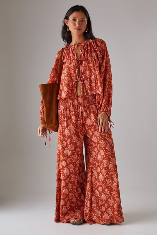 Cheesecloth fabric with delicate floral pattern throughout
        Relaxed boho silhouette with feminine tie-front detail
        Gathered neckline creating elegant volume
        Long sleeves with elasticated cuffs for comfortable wear
        Versatile design perfect for coordinating with matching trousers or styling separately
    
    This Warehouse cheesecloth blouse captures effortless bohemian style with its flowing silhouette and charming tie-front detail. The gathered neckline creates a flattering frame for delicate jewellery, whilst the lightweight fabric drapes beautifully for a relaxed yet feminine look. Style with the coordinating wide-leg trousers as seen on our model for a contemporary co-ord effect, or pair with your favourite denim and flat sandals for casual daytime outings. For a more structured daytime look, tuck the front into high-waisted trousers and add a leather tote bag. This versatile piece transitions seamlessly from family brunches to afternoon garden parties - simply swap your trainers for espadrilles and add statement earrings to refresh your look.