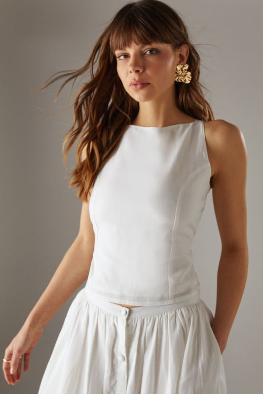 Sleek racer neckline with striking cross-back detail for a contemporary silhouette
        Cropped length perfect for high-waisted styling options
        Linen blend fabric offers breathable comfort with a natural texture
        Tie-back fastening allows for customisable fit
        Versatile design transitions effortlessly from day to evening wear
    
    This sophisticated crop top showcases a distinctive racer front with an eye-catching cross-back design that reveals just the right amount of skin. The textured linen blend fabric creates a refined yet relaxed aesthetic that's perfect for warm-weather styling. Pair with the matching wide-leg culottes as shown for a coordinated ensemble that radiates effortless chic, or style with high-waisted denim and strappy sandals for casual daytime events. For family gatherings or weekend brunches, layer with a lightweight cardigan and accessorise with statement earrings to enhance the look. The versatile nature of this piece makes it an essential addition to your summer wardrobe, offering countless styling possibilities whilst maintaining that confident Warehouse edge. The cropped silhouette works beautifully with higher-rise bottoms to create a balanced and flattering proportion.
