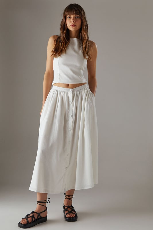 Sleek racer neckline with striking cross-back detail for a contemporary silhouette
        Cropped length perfect for high-waisted styling options
        Linen blend fabric offers breathable comfort with a natural texture
        Tie-back fastening allows for customisable fit
        Versatile design transitions effortlessly from day to evening wear
    
    This sophisticated crop top showcases a distinctive racer front with an eye-catching cross-back design that reveals just the right amount of skin. The textured linen blend fabric creates a refined yet relaxed aesthetic that's perfect for warm-weather styling. Pair with the matching wide-leg culottes as shown for a coordinated ensemble that radiates effortless chic, or style with high-waisted denim and strappy sandals for casual daytime events. For family gatherings or weekend brunches, layer with a lightweight cardigan and accessorise with statement earrings to enhance the look. The versatile nature of this piece makes it an essential addition to your summer wardrobe, offering countless styling possibilities whilst maintaining that confident Warehouse edge. The cropped silhouette works beautifully with higher-rise bottoms to create a balanced and flattering proportion.