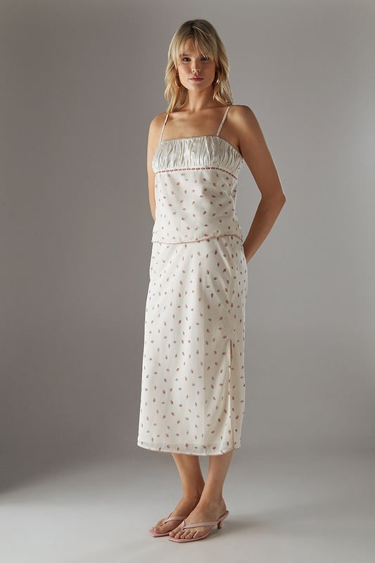 Feminine milkmaid-style top with delicate ruched bust detail
        Charming lace trim adds a touch of vintage-inspired elegance
        Adjustable thin straps for a personalised fit
        Dainty all-over pattern creates visual interest
        Back tie detail allows for customised styling
    
    This Warehouse ruched bust top captures the essence of carefree summer style with its romantic milkmaid silhouette. The delicate lace trim and ruched detailing create a feminine aesthetic that's both current and timeless. Perfect for daytime outings, style this versatile piece with your favourite denim and trainers for a casual coffee date, or pair with a flowing midi skirt and sandals for family gatherings. The loose fit offers comfortable wear throughout the day whilst maintaining a flattering shape. For cooler evenings, layer with a lightweight cardigan or denim jacket to extend its wearability. The adjustable straps and back tie detail allow you to customise the fit to your preference, making this top a wardrobe staple that transitions effortlessly from casual brunches to afternoon garden parties.