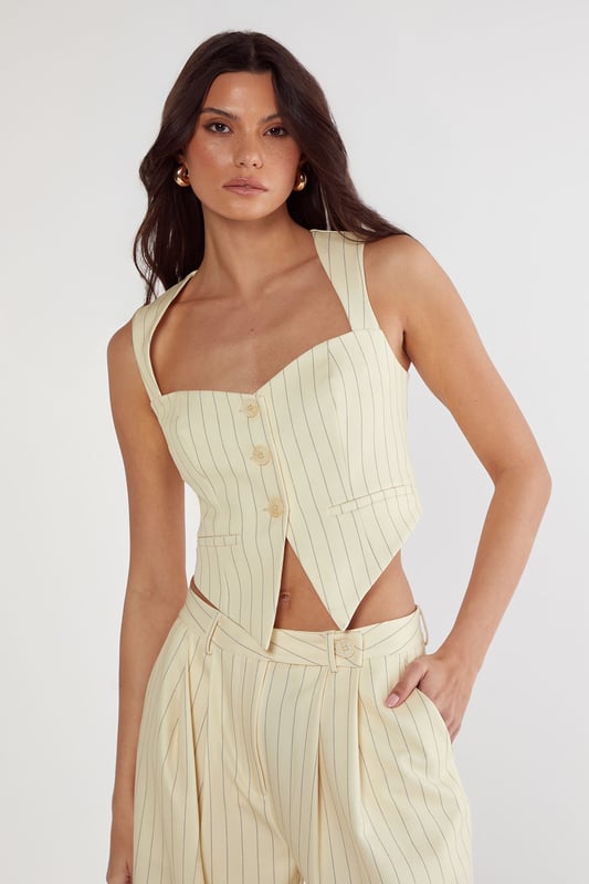 Tailored vest with elegant pinstripe pattern throughout
        Structured sweetheart neckline with button-front closure
        Halter-style straps for a sophisticated silhouette
        Cropped length perfect for contemporary workwear styling
        Fitted design with subtle back detailing for a polished finish
    
    This Nasty Gal tailored vest reimagines office attire with contemporary flair. The structured silhouette and classic pinstripe pattern create a professional look whilst the cropped length and sweetheart neckline add a modern twist. Style with the matching wide-leg trousers as shown for a coordinated ensemble that commands attention in the boardroom. For a more versatile approach, pair with high-waisted tailored trousers and a crisp white shirt underneath. Complete your workwear look with minimal jewellery and pointed court shoes for meetings, or dress down with loafers for casual Friday. This versatile piece transitions seamlessly from day to evening - simply add statement earrings and a clutch bag for after-work gatherings. The vest's structured design flatters the figure whilst maintaining workplace appropriateness.