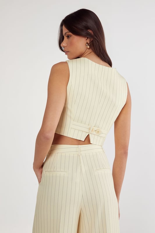 Tailored vest with elegant pinstripe pattern throughout
        Structured sweetheart neckline with button-front closure
        Halter-style straps for a sophisticated silhouette
        Cropped length perfect for contemporary workwear styling
        Fitted design with subtle back detailing for a polished finish
    
    This Nasty Gal tailored vest reimagines office attire with contemporary flair. The structured silhouette and classic pinstripe pattern create a professional look whilst the cropped length and sweetheart neckline add a modern twist. Style with the matching wide-leg trousers as shown for a coordinated ensemble that commands attention in the boardroom. For a more versatile approach, pair with high-waisted tailored trousers and a crisp white shirt underneath. Complete your workwear look with minimal jewellery and pointed court shoes for meetings, or dress down with loafers for casual Friday. This versatile piece transitions seamlessly from day to evening - simply add statement earrings and a clutch bag for after-work gatherings. The vest's structured design flatters the figure whilst maintaining workplace appropriateness.