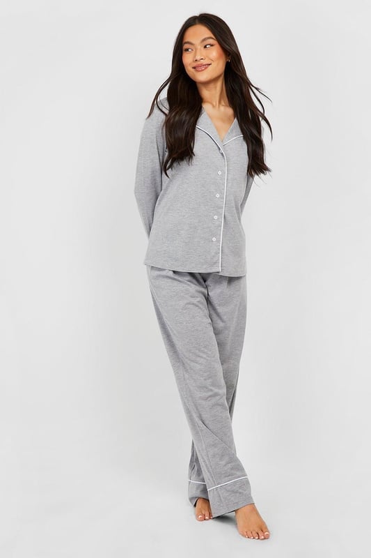 Stylish button-through jersey pyjama set
        Contrasting piping detail for a chic look
        Long sleeves with cuffed ends for extra comfort
        Wide-leg trousers for unrestricted movement
        Soft jersey fabric ensures a cosy night's sleep
    
    Indulge in the ultimate bedtime luxury with this long sleeve button-through jersey PJ set from Boohoo. Perfect for those who appreciate both style and comfort, this set combines a classic silhouette with modern details. The contrasting piping along the collar, cuffs, and trouser hems adds a touch of sophistication to your nighttime ensemble. The wide-leg trousers offer freedom of movement, ideal for restless sleepers or lazy weekend mornings. Whether you're having a girls' night in or simply unwinding after a long day, this versatile set is your go-to choice. Pair with fluffy slippers and a warm dressing gown for those chilly evenings, or wear the top with your favourite jeans for a casual daytime look. This PJ set isn't just for sleeping - it's for living your best, most comfortable life.