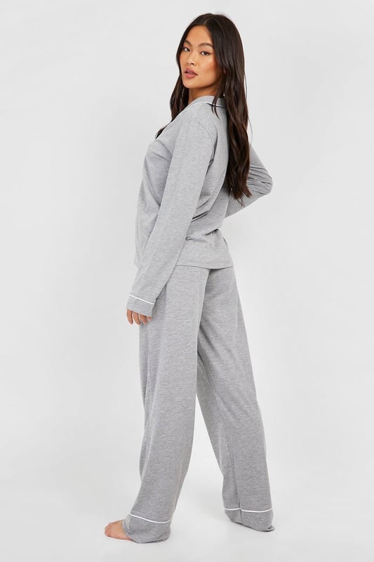 Stylish button-through jersey pyjama set
        Contrasting piping detail for a chic look
        Long sleeves with cuffed ends for extra comfort
        Wide-leg trousers for unrestricted movement
        Soft jersey fabric ensures a cosy night's sleep
    
    Indulge in the ultimate bedtime luxury with this long sleeve button-through jersey PJ set from Boohoo. Perfect for those who appreciate both style and comfort, this set combines a classic silhouette with modern details. The contrasting piping along the collar, cuffs, and trouser hems adds a touch of sophistication to your nighttime ensemble. The wide-leg trousers offer freedom of movement, ideal for restless sleepers or lazy weekend mornings. Whether you're having a girls' night in or simply unwinding after a long day, this versatile set is your go-to choice. Pair with fluffy slippers and a warm dressing gown for those chilly evenings, or wear the top with your favourite jeans for a casual daytime look. This PJ set isn't just for sleeping - it's for living your best, most comfortable life.
