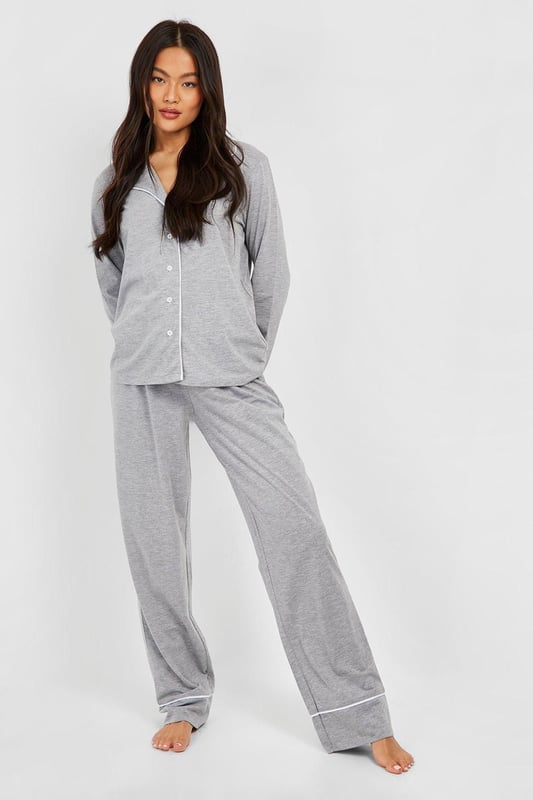 Stylish button-through jersey pyjama set
        Contrasting piping detail for a chic look
        Long sleeves with cuffed ends for extra comfort
        Wide-leg trousers for unrestricted movement
        Soft jersey fabric ensures a cosy night's sleep
    
    Indulge in the ultimate bedtime luxury with this long sleeve button-through jersey PJ set from Boohoo. Perfect for those who appreciate both style and comfort, this set combines a classic silhouette with modern details. The contrasting piping along the collar, cuffs, and trouser hems adds a touch of sophistication to your nighttime ensemble. The wide-leg trousers offer freedom of movement, ideal for restless sleepers or lazy weekend mornings. Whether you're having a girls' night in or simply unwinding after a long day, this versatile set is your go-to choice. Pair with fluffy slippers and a warm dressing gown for those chilly evenings, or wear the top with your favourite jeans for a casual daytime look. This PJ set isn't just for sleeping - it's for living your best, most comfortable life.