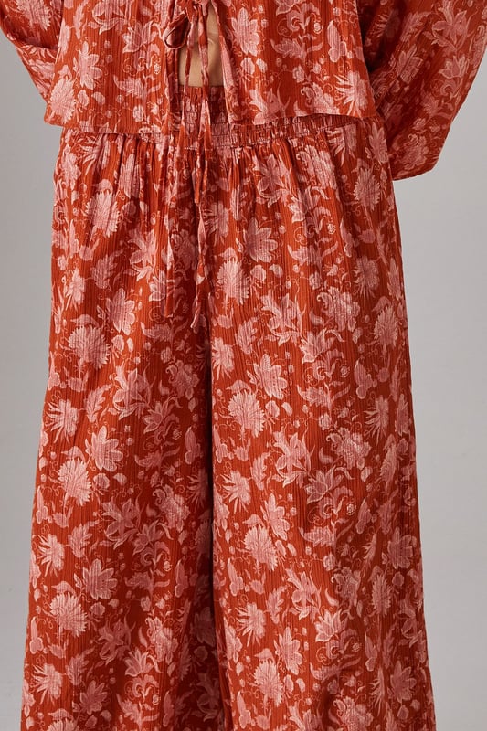 Lightweight cheesecloth fabric with all-over print creates a breezy, effortless silhouette
        Shirred waistband offers comfortable stretch whilst defining the waist
        Dramatic wide leg cut provides maximum movement and a fashion-forward profile
        Floor-skimming length creates an elongated, elegant line
        Coordinating top available for a striking head-to-toe ensemble
    
    These statement wide leg trousers combine comfort with contemporary style for your everyday wardrobe. The shirred waistband creates a flattering fit that sits perfectly at your natural waist, whilst the flowing wide leg cut delivers a relaxed yet sophisticated silhouette. Style with the matching top as seen on our model for a coordinated daytime look, or pair with a simple fitted tee and trainers for casual weekend brunches. The lightweight cheesecloth fabric makes these trousers ideal for warmer days or layering during transitional seasons. Add a chunky knit and ankle boots when temperatures drop, or dress up with metallic sandals and a woven tote for garden parties or al fresco dining. These versatile trousers will quickly become your go-to for effortless daywear styling.