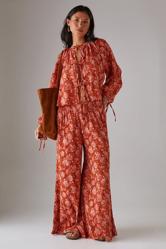 Lightweight cheesecloth fabric with all-over print creates a breezy, effortless silhouette
        Shirred waistband offers comfortable stretch whilst defining the waist
        Dramatic wide leg cut provides maximum movement and a fashion-forward profile
        Floor-skimming length creates an elongated, elegant line
        Coordinating top available for a striking head-to-toe ensemble
    
    These statement wide leg trousers combine comfort with contemporary style for your everyday wardrobe. The shirred waistband creates a flattering fit that sits perfectly at your natural waist, whilst the flowing wide leg cut delivers a relaxed yet sophisticated silhouette. Style with the matching top as seen on our model for a coordinated daytime look, or pair with a simple fitted tee and trainers for casual weekend brunches. The lightweight cheesecloth fabric makes these trousers ideal for warmer days or layering during transitional seasons. Add a chunky knit and ankle boots when temperatures drop, or dress up with metallic sandals and a woven tote for garden parties or al fresco dining. These versatile trousers will quickly become your go-to for effortless daywear styling.
