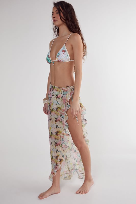 Flowing woven cotton beach skirt with eye-catching tie-dye pattern
        Feminine ruffle detailing along the edges for added movement
        High-slit design offering adjustable coverage and effortless movement
        Lightweight fabric perfect for warm-weather destinations
        Versatile wrap style that can be tied at desired height
    
    This breezy Nasty Gal beach skirt combines carefree style with practical beachwear functionality. The lightweight cotton construction ensures comfort during hot days by the shore, while the distinctive tie-dye pattern captures the essence of summer escapism. Wrap it around your waist as a chic cover-up when heading from the beach to a seaside caf, or style it with a matching triangle bikini top as shown for a coordinated look. The ruffle detailing adds a playful, feminine touch that catches the gentle sea breeze beautifully. Perfect for your holiday wardrobe, this versatile piece transitions effortlessly from poolside lounging to casual sunset strolls along the promenade. Pair with simple sandals and statement jewellery for an impromptu beach party, or throw on over your favourite swimwear for instant style when the ice cream van arrives.
