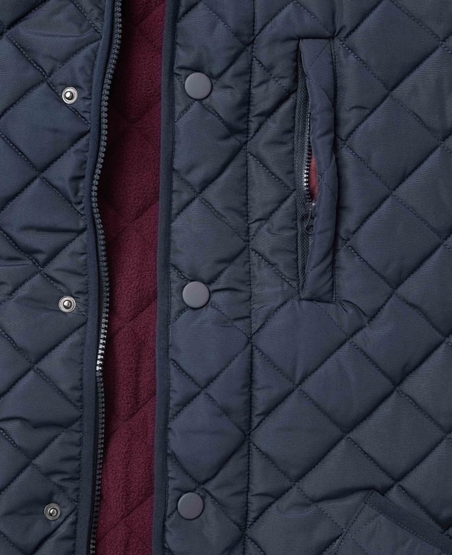 This quilted jacket was the go-to choice for discerning gentlemen last winter - and it's back again to elevate your winter style. Crafted for warmth without restriction, it features refined cotton corduroy trim and multiple pockets to keep your daily essentials at hand. Whether you're navigating city streets or venturing into the countryside, this jacket blends functionality with timeless appeal. Made from 100% polyester quilted outer with a 100% polyester navy lining. Centre back length on size Medium is 72 cm. Edges trimmed in 100% cotton corduroy. Medium weight wadding for extra warmth. Regular fit. Two patch pockets and zipped pocket; back has a poppered flap; matte navy matching studs.
