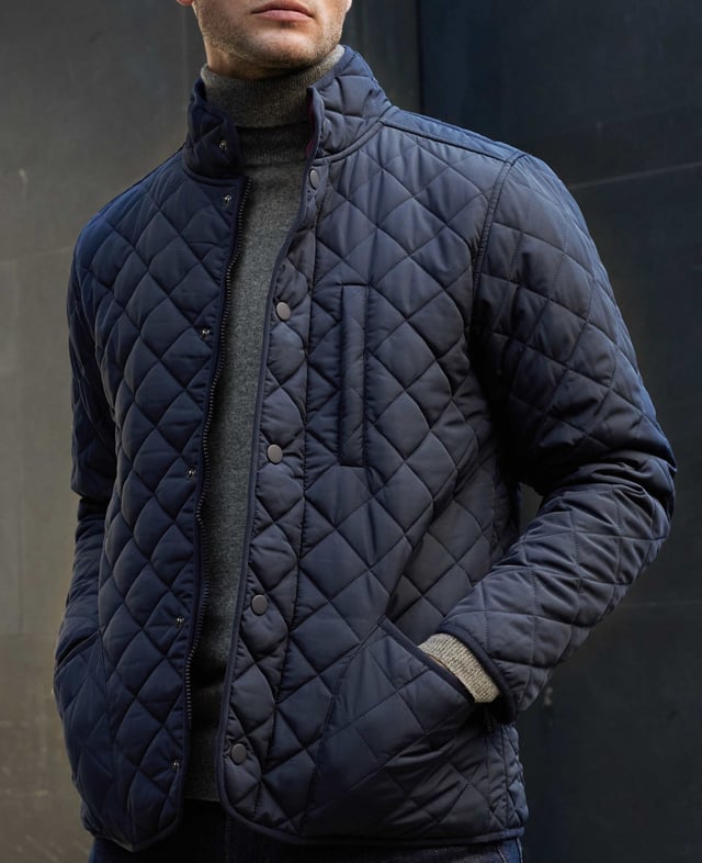 This quilted jacket was the go-to choice for discerning gentlemen last winter - and it's back again to elevate your winter style. Crafted for warmth without restriction, it features refined cotton corduroy trim and multiple pockets to keep your daily essentials at hand. Whether you're navigating city streets or venturing into the countryside, this jacket blends functionality with timeless appeal. Made from 100% polyester quilted outer with a 100% polyester navy lining. Centre back length on size Medium is 72 cm. Edges trimmed in 100% cotton corduroy. Medium weight wadding for extra warmth. Regular fit. Two patch pockets and zipped pocket; back has a poppered flap; matte navy matching studs.