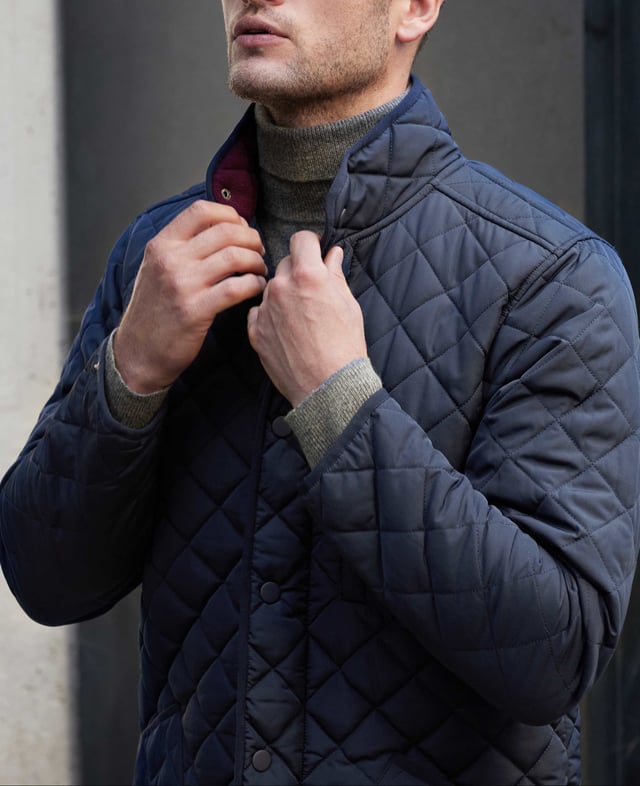 This quilted jacket was the go-to choice for discerning gentlemen last winter - and it's back again to elevate your winter style. Crafted for warmth without restriction, it features refined cotton corduroy trim and multiple pockets to keep your daily essentials at hand. Whether you're navigating city streets or venturing into the countryside, this jacket blends functionality with timeless appeal. Made from 100% polyester quilted outer with a 100% polyester navy lining. Centre back length on size Medium is 72 cm. Edges trimmed in 100% cotton corduroy. Medium weight wadding for extra warmth. Regular fit. Two patch pockets and zipped pocket; back has a poppered flap; matte navy matching studs.
