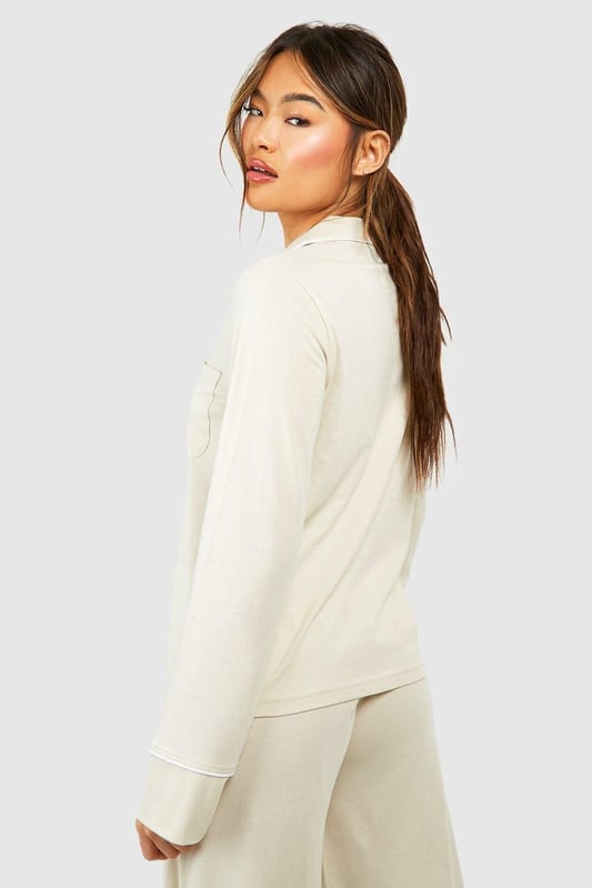 Collared button-front design for a classic look
        Soft jersey fabric for ultimate comfort
        Long sleeves with cuffed details
        Relaxed fit for effortless lounging
        Versatile piece that can be styled for various occasions
    
    Embrace laid-back luxury with this Button Front Lounge Shirt from Boohoo. Perfect for those cosy nights in or lazy weekend mornings, this versatile piece combines style and comfort effortlessly. The classic collared design adds a touch of sophistication to your loungewear collection, while the soft jersey fabric ensures you stay comfortable all day long. Pair it with the matching trousers for a coordinated look, or throw it over your favourite leggings for a more casual vibe. Whether you're binge-watching your latest TV obsession or hosting an intimate brunch with friends, this lounge shirt is your go-to for looking put-together without sacrificing comfort. Its adaptable nature means you can easily dress it up with some statement jewellery for those impromptu video calls or keep it simple for a relaxed day at home. With Boohoo's Button Front Lounge Shirt, you'll redefine your at-home style game.