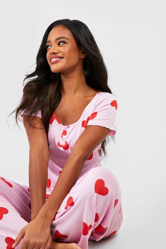 Charming heart print pyjama set
        Button-front top with short sleeves
        Scoop neckline for a feminine touch
        Comfortable wide-leg trousers
        Soft jersey fabric for ultimate comfort
    
    Indulge in sweet dreams with this adorable heart print pyjama set from Boohoo. Perfect for the fashion-forward sleeper, this ensemble combines style and comfort effortlessly. The button-front top features a flattering scoop neckline and short sleeves, ideal for those warm nights. Paired with wide-leg trousers, this set offers unrestricted movement for a restful slumber. The soft jersey fabric ensures a cosy feel against your skin, making it perfect for lounging on lazy weekends or having a girls' night in. Whether you're settling down for a Netflix marathon or enjoying your morning coffee, these pyjamas will keep you feeling chic and comfortable. Embrace your playful side and add a touch of romance to your nightwear collection with this charming set that's sure to become a bedtime favourite.