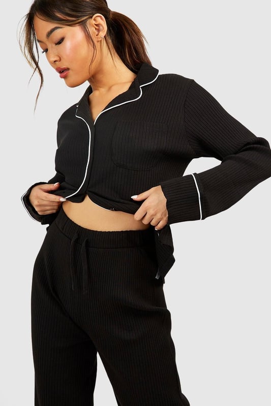Ribbed jersey fabric for comfort and texture
        Tie waist detail for adjustable fit
        Wide-leg design for relaxed silhouette
        Matching cropped jacket with contrasting piping
        Versatile two-piece set for effortless lounging
    
    Embrace laid-back luxury with this rib tie waist lounge trouser set from Boohoo. Perfect for those cosy nights in or lazy weekend mornings, this ensemble offers both style and comfort. The wide-leg trousers feature a flattering high waist with an adjustable tie, allowing you to customise your fit. Pair with the matching cropped jacket, adorned with chic contrasting piping, for a coordinated look that's anything but ordinary. Whether you're binge-watching your favourite series or hosting an intimate brunch at home, this set will keep you feeling fabulous and relaxed. Style with soft slippers and your favourite oversized cardigan for ultimate comfort, or dress it up with statement earrings and a messy bun for those impromptu video calls. This Boohoo loungewear set is the epitome of effortless chic, ensuring you look put-together even on your most casual days.