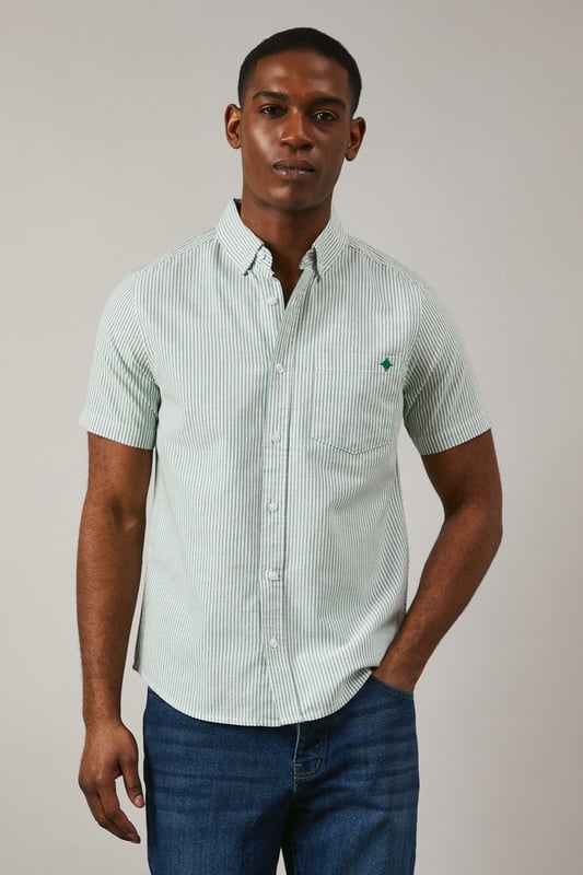 Classic Oxford stripe pattern for timeless appeal
        Short sleeves ideal for warmer weather
        Button-down collar for a smart-casual look
        Chest pocket with embroidered logo detail
        Back pleat for enhanced comfort and movement
    
    This Maine Oxford stripe short sleeve shirt is a versatile addition to any gentleman's wardrobe. The crisp woven fabric and classic stripe pattern create a smart yet relaxed aesthetic, perfect for various casual occasions. Style it effortlessly with dark denim jeans and white trainers for a laid-back weekend look, or pair it with chino shorts and boat shoes for a seaside stroll. The button-down collar adds a touch of refinement, making it suitable for casual Fridays at the office when worn with tailored trousers. Whether you're attending a family barbecue, meeting friends for a pub lunch, or enjoying a sunny day out, this shirt offers both comfort and style. Its breathable cotton composition ensures you stay cool and collected, while the back pleat allows for ease of movement. Embrace the timeless charm of this Oxford shirt and make it your go-to for effortless, British casual style.