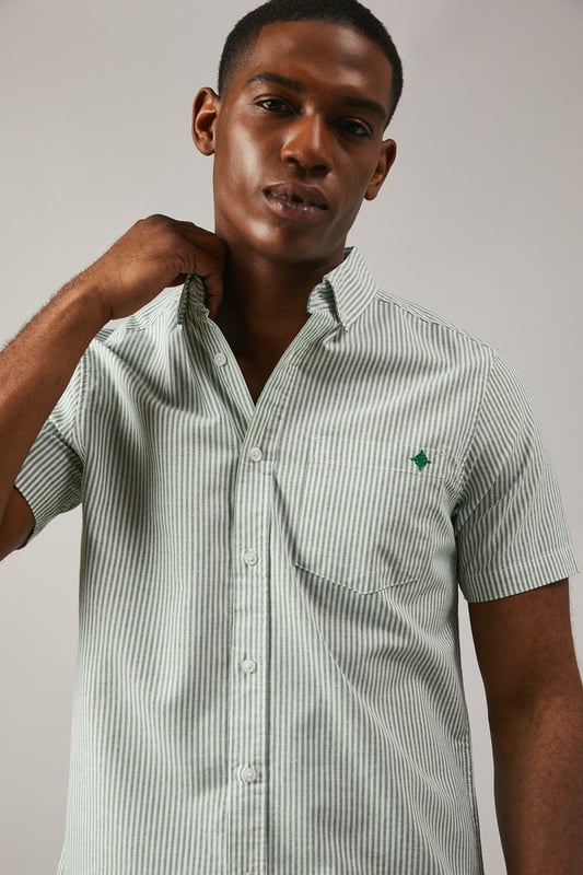 Classic Oxford stripe pattern for timeless appeal
        Short sleeves ideal for warmer weather
        Button-down collar for a smart-casual look
        Chest pocket with embroidered logo detail
        Back pleat for enhanced comfort and movement
    
    This Maine Oxford stripe short sleeve shirt is a versatile addition to any gentleman's wardrobe. The crisp woven fabric and classic stripe pattern create a smart yet relaxed aesthetic, perfect for various casual occasions. Style it effortlessly with dark denim jeans and white trainers for a laid-back weekend look, or pair it with chino shorts and boat shoes for a seaside stroll. The button-down collar adds a touch of refinement, making it suitable for casual Fridays at the office when worn with tailored trousers. Whether you're attending a family barbecue, meeting friends for a pub lunch, or enjoying a sunny day out, this shirt offers both comfort and style. Its breathable cotton composition ensures you stay cool and collected, while the back pleat allows for ease of movement. Embrace the timeless charm of this Oxford shirt and make it your go-to for effortless, British casual style.