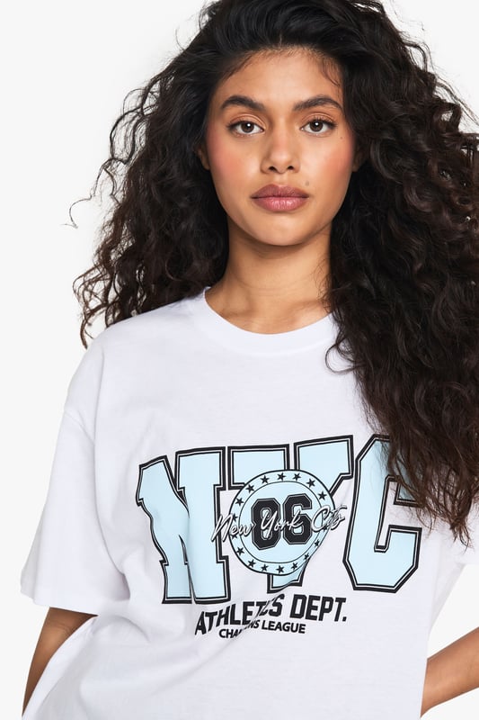 Oversized fit for ultimate comfort and laid-back style
        Bold NYC Athletics Dept graphic print for a sporty urban vibe
        Versatile cotton fabric suitable for all-day wear
        Short sleeves and crew neckline for a classic T-shirt silhouette
        Relaxed dropped shoulders enhancing the casual look
    
    Embrace the urban-chic aesthetic with this oversized T-shirt featuring a striking NYC Athletics Dept print. Perfect for those seeking a blend of comfort and style, this versatile piece is ideal for casual outings or relaxed weekends. Pair it with gingham shorts as shown for a playful contrast, or style it with your favourite denim for an effortless everyday look. The roomy fit allows for easy layering - throw on a denim jacket for cooler evenings or wear it over a long-sleeved top when the temperature drops. Dress it up with a leather skirt and trainers for a trendy night out, or keep it casual with joggers for a quick coffee run. This T-shirt is a must-have for the fashion-forward individual who values both comfort and street-style credibility.