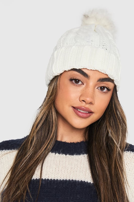 Chunky cable knit design for a classic winter look
        Soft acrylic fabric for comfort and warmth
        Oversized faux fur pom-pom for a playful touch
        Ribbed cuff for a snug fit
        Versatile one-size-fits-all styling
    
    Embrace the chilly weather with this charming Cable Knit Faux Pom Beanie from Boohoo. The chunky cable knit pattern adds a timeless appeal, while the oversized faux fur pom-pom injects a dash of fun to your winter ensemble. Perfect for casual outings or family gatherings, this beanie pairs effortlessly with your favourite jumper and jeans combo. For a trendy look, team it with a longline puffer coat, thermal leggings, and chunky trainers. The versatile design makes it an ideal accessory for various cold-weather activities, from ice skating with friends to cosy walks in the park. With its soft acrylic fabric and snug fit, this beanie ensures you stay warm and stylish throughout the season.