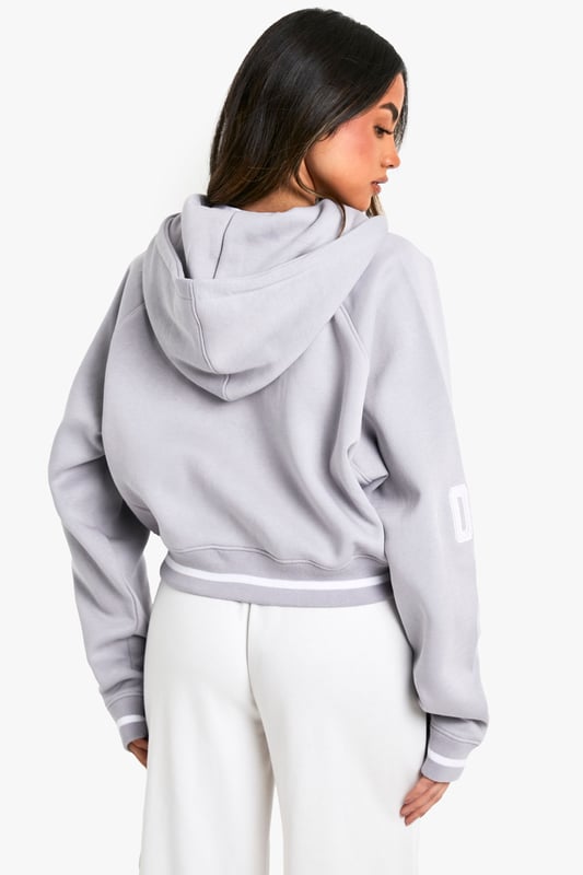Cropped design for a trendy silhouette
        Full-length zip closure for versatile styling
        Bold 'New York' slogan across the chest
        '06' detail on the sleeve for a sporty touch
        Comfortable hood for added warmth and style
    
    Make a statement with this eye-catching cropped hoodie, perfect for the fashion-forward trendsetter. The bold 'New York' slogan and '06' detail give it an urban, street-style edge that's sure to turn heads. Its versatile design allows for effortless styling - pair it with high-waisted trousers and trainers for a casual daytime look, or throw it over a bodycon dress for an edgy night out ensemble. The full-length zip offers adaptability, allowing you to customise your look to suit the occasion or weather. Ideal for everything from coffee dates to weekend shopping trips, this hoodie is a must-have addition to any casual wardrobe. Its cosy hood and soft fabric ensure comfort without compromising on style, making it the perfect go-to piece for those days when you want to look effortlessly cool.