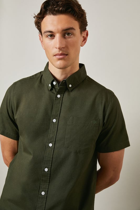 Textured woven cotton fabric with subtle surface detail for added visual interest
        Classic button-down collar with short sleeves for warm-weather comfort
        Clean-cut design featuring a single back pleat for improved movement
        Traditional front button fastening with contrasting white buttons
        Versatile regular fit that suits a variety of body types
    
    This Maine textured short sleeve shirt combines timeless style with everyday practicality. The breathable cotton construction ensures all-day comfort whilst the subtle texture adds character to this wardrobe essential. Perfect for casual weekend outings, pair it with dark shorts and white trainers as shown for an effortlessly cool summer look. The versatile design also works brilliantly with chinos or jeans for family gatherings or informal social events. Layer under a lightweight jacket when the temperature drops or wear it unbuttoned over a plain t-shirt for a more relaxed approach. The button-down collar maintains a smart appearance even without a tie, making this shirt an ideal choice for those occasions that sit between casual and smart-casual. Machine washable at 30 degrees, it's designed to maintain its shape and appearance with proper care.