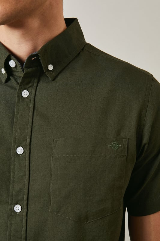 Textured woven cotton fabric with subtle surface detail for added visual interest
        Classic button-down collar with short sleeves for warm-weather comfort
        Clean-cut design featuring a single back pleat for improved movement
        Traditional front button fastening with contrasting white buttons
        Versatile regular fit that suits a variety of body types
    
    This Maine textured short sleeve shirt combines timeless style with everyday practicality. The breathable cotton construction ensures all-day comfort whilst the subtle texture adds character to this wardrobe essential. Perfect for casual weekend outings, pair it with dark shorts and white trainers as shown for an effortlessly cool summer look. The versatile design also works brilliantly with chinos or jeans for family gatherings or informal social events. Layer under a lightweight jacket when the temperature drops or wear it unbuttoned over a plain t-shirt for a more relaxed approach. The button-down collar maintains a smart appearance even without a tie, making this shirt an ideal choice for those occasions that sit between casual and smart-casual. Machine washable at 30 degrees, it's designed to maintain its shape and appearance with proper care.
