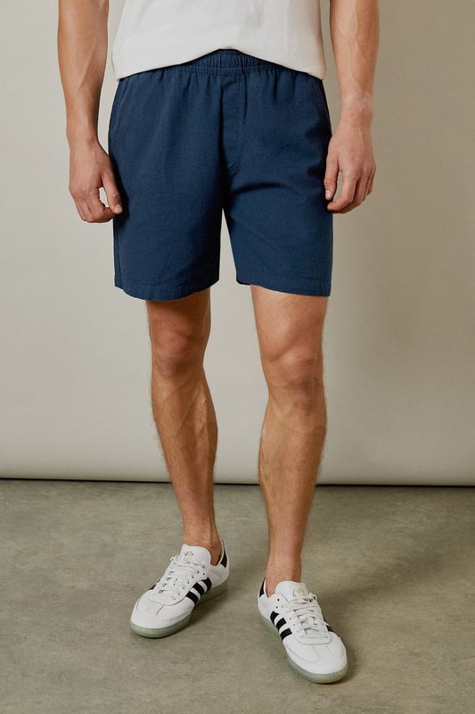 Textured woven fabric with distinctive marl finish for added visual interest
        Comfortable elasticated waistband for an easy, relaxed fit
        Practical back pocket for essential items
        Mid-thigh length offering the perfect balance between comfort and style
        Versatile navy hue that pairs effortlessly with your existing wardrobe
    
    These Burton textured casual shorts deliver the perfect combination of comfort and laid-back style for the modern man. The cotton fabric provides breathability for those warmer days, whether you're heading to a weekend BBQ or watching the match at your local. Style them as shown with a crisp white t-shirt and trainers for an effortless daytime look, or pair with a short-sleeved shirt for casual gatherings with friends and family. The relaxed fit ensures all-day comfort without compromising on style, making these shorts a versatile addition to your summer rotation. They're ideal for sporting events, pub garden sessions, or simply lounging at home. Machine washable at 30 degrees, these shorts offer practicality alongside their casual charm - a true wardrobe essential for the British summer.