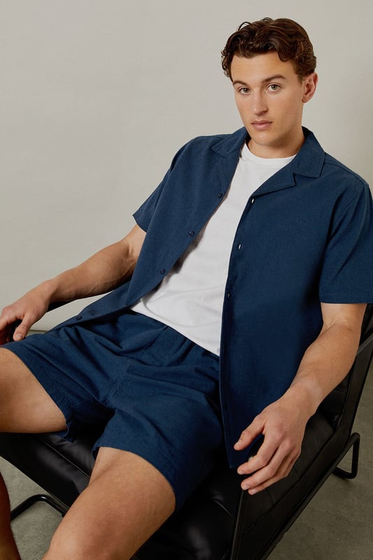 Textured woven fabric with distinctive marl finish for added visual interest
        Comfortable elasticated waistband for an easy, relaxed fit
        Practical back pocket for essential items
        Mid-thigh length offering the perfect balance between comfort and style
        Versatile navy hue that pairs effortlessly with your existing wardrobe
    
    These Burton textured casual shorts deliver the perfect combination of comfort and laid-back style for the modern man. The cotton fabric provides breathability for those warmer days, whether you're heading to a weekend BBQ or watching the match at your local. Style them as shown with a crisp white t-shirt and trainers for an effortless daytime look, or pair with a short-sleeved shirt for casual gatherings with friends and family. The relaxed fit ensures all-day comfort without compromising on style, making these shorts a versatile addition to your summer rotation. They're ideal for sporting events, pub garden sessions, or simply lounging at home. Machine washable at 30 degrees, these shorts offer practicality alongside their casual charm - a true wardrobe essential for the British summer.