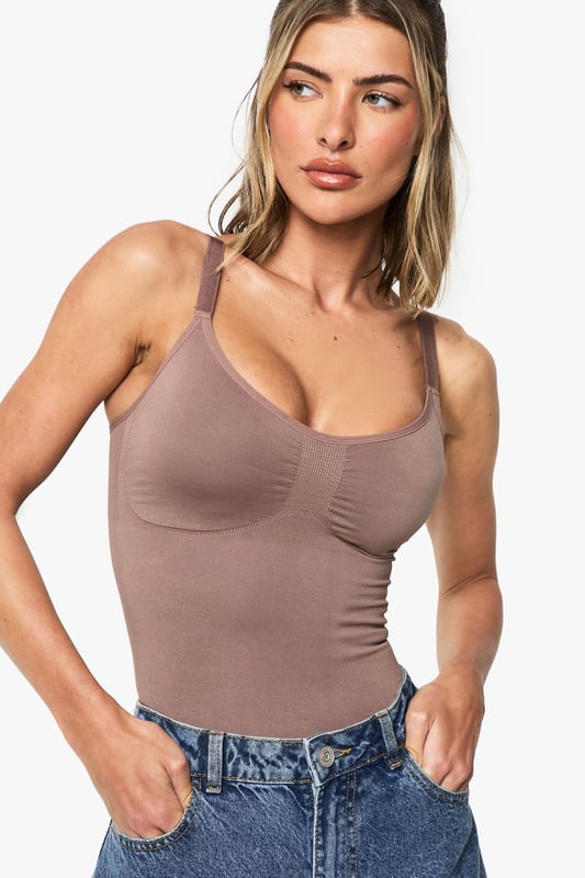 Seamless construction for a smooth, second-skin feel
        Sculpting design that contours to your natural shape
        Sleeveless silhouette with supportive straps
        Scoop neckline with subtle ruching detail
        Form-fitting bodysuit that tucks perfectly into bottoms
    
    This versatile seamless bodysuit is the foundation piece your wardrobe has been waiting for. The sculpting fabric gently hugs your curves whilst the sleeveless design offers unrestricted movement for all-day comfort. As seen on our model, pair with classic denim jeans for an effortlessly chic daytime look, or style with a flowing midi skirt and statement jewellery for casual evening gatherings. The scoop neckline frames your dcolletage beautifully, whilst the smooth, form-fitting silhouette creates a flattering line under any outfit. Perfect for layering under sheer blouses or wearing as a statement piece on its own, this Boohoo bodysuit transitions seamlessly from coffee dates to family brunches. Add a structured blazer and wide-leg trousers for a contemporary twist on casual sophistication.
