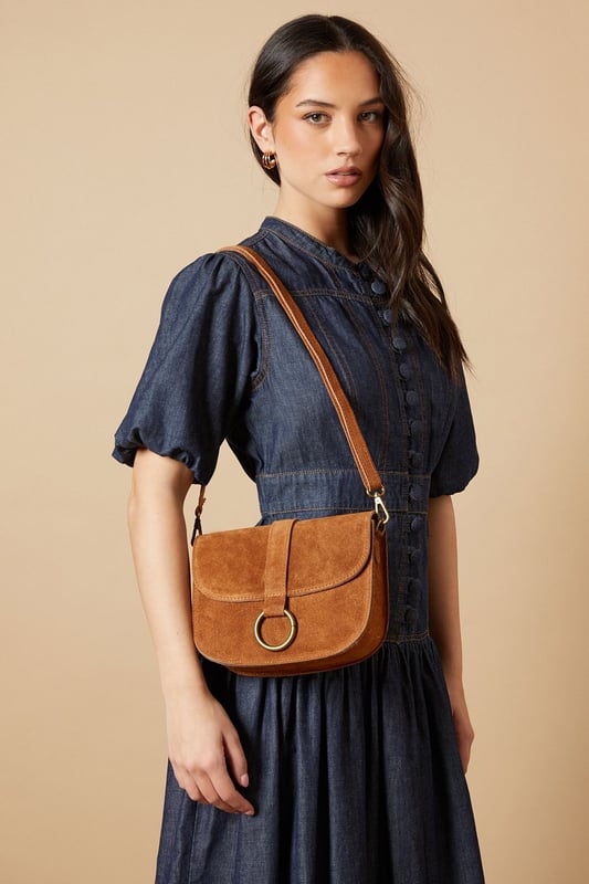Structured saddle bag silhouette with distinctive curved edges
        Statement gold-tone ring detail on the front flap closure
        Adjustable cross body strap for versatile wearing options
        Suede finish for a tactile, luxurious feel
        Compact yet practical interior with enough space for daily essentials
    
    The Thessina Saddle Bag from Oasis combines timeless design with contemporary detailing. The structured silhouette maintains its shape throughout the day, whilst the distinctive gold-tone ring hardware adds a touch of sophistication. Perfect for daytime outings, this versatile bag complements casual ensembles beautifully. Style with a floaty white dress and ankle boots for weekend brunches, or pair with jeans and a crisp blouse for shopping trips with friends. The adjustable strap allows for comfortable wear across the body, keeping your hands free for browsing or holding a coffee. This bag strikes the ideal balance between fashion and function - small enough to remain unobtrusive yet roomy enough to hold your phone, wallet, keys and favourite lipstick for quick touch-ups throughout the day.