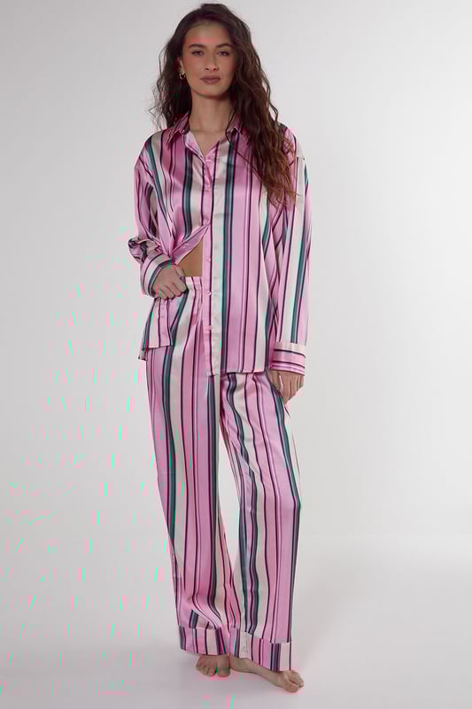 Luxurious satin finish with eye-catching multi-stripe pattern throughout
        Oversized shirt design with classic collar and button-through front
        Long sleeves with contrast piping detail at cuffs
        Relaxed fit trousers with wide leg silhouette for ultimate comfort
        Coordinated set designed for effortless nightwear styling
    
    Embrace laid-back luxury with this striking satin pyjama set from Nasty Gal. The oversized shirt silhouette offers a contemporary twist on classic nightwear, whilst the vibrant stripe pattern adds a playful touch to your evening routine. Perfect for those who appreciate comfort without compromising on style, this set transitions seamlessly from night to morning. Pair with fluffy slippers for cosy nights in, or throw on with trainers for a quick dash to the corner shop. The relaxed wide-leg trousers provide unrestricted movement, making this set ideal for lounging during family gatherings or weekend brunches at home. The contrasting piped trim adds a refined finishing touch to this already standout set, ensuring you look put-together even in your downtime.