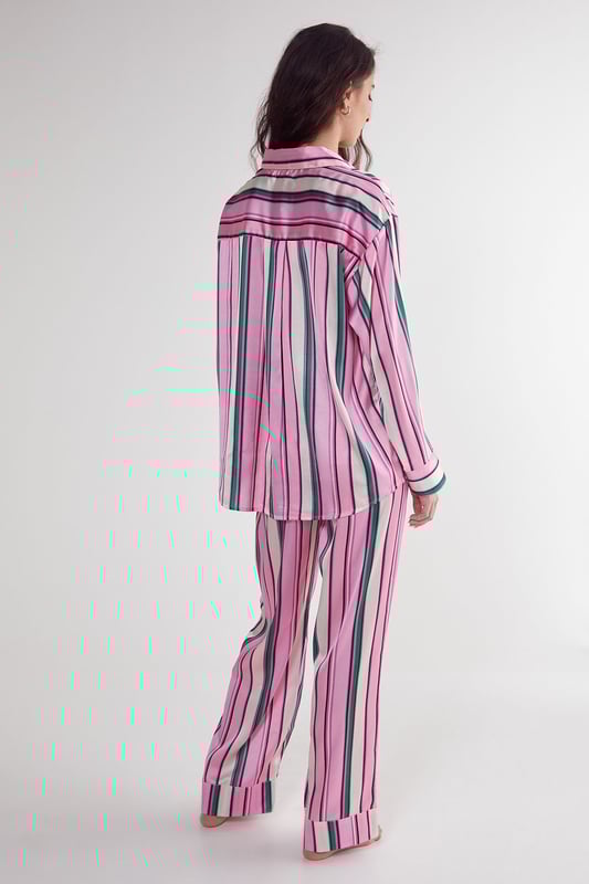 Luxurious satin finish with eye-catching multi-stripe pattern throughout
        Oversized shirt design with classic collar and button-through front
        Long sleeves with contrast piping detail at cuffs
        Relaxed fit trousers with wide leg silhouette for ultimate comfort
        Coordinated set designed for effortless nightwear styling
    
    Embrace laid-back luxury with this striking satin pyjama set from Nasty Gal. The oversized shirt silhouette offers a contemporary twist on classic nightwear, whilst the vibrant stripe pattern adds a playful touch to your evening routine. Perfect for those who appreciate comfort without compromising on style, this set transitions seamlessly from night to morning. Pair with fluffy slippers for cosy nights in, or throw on with trainers for a quick dash to the corner shop. The relaxed wide-leg trousers provide unrestricted movement, making this set ideal for lounging during family gatherings or weekend brunches at home. The contrasting piped trim adds a refined finishing touch to this already standout set, ensuring you look put-together even in your downtime.