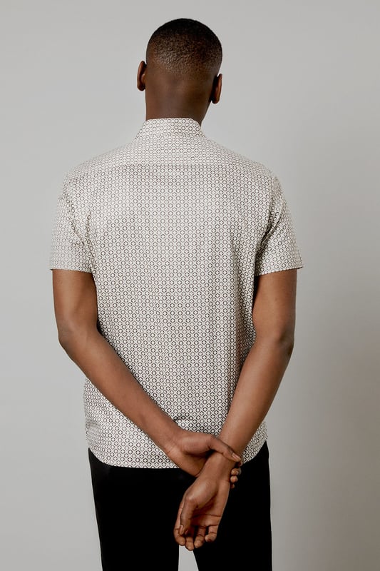 Distinctive all-over print design
        Classic short sleeve silhouette
        Comfortable woven cotton fabric
        Versatile button-up style
        Tailored fit for a smart-casual look
    
    This Burton short sleeve shirt is the perfect addition to your casual wardrobe. The distinctive all-over print adds character to this classic piece, making it ideal for various occasions. Whether you're heading to the pub with mates or attending a family gathering, this shirt has you covered. Style it with dark trousers and trainers for a laid-back yet put-together look, as shown in the images. For a more relaxed vibe, leave it unbuttoned over a plain t-shirt. The woven cotton fabric ensures comfort throughout the day, while the tailored fit creates a smart silhouette without compromising on ease of movement. This versatile shirt is a must-have for the modern British gent who appreciates timeless style with a contemporary twist.