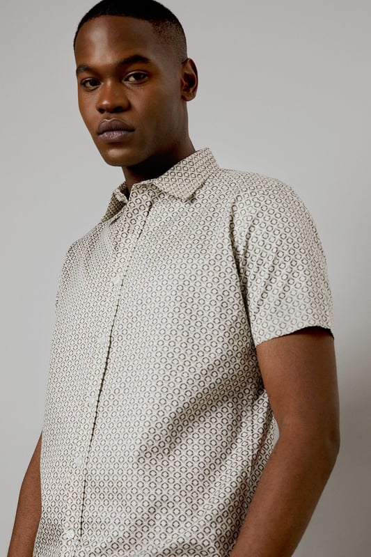 Distinctive all-over print design
        Classic short sleeve silhouette
        Comfortable woven cotton fabric
        Versatile button-up style
        Tailored fit for a smart-casual look
    
    This Burton short sleeve shirt is the perfect addition to your casual wardrobe. The distinctive all-over print adds character to this classic piece, making it ideal for various occasions. Whether you're heading to the pub with mates or attending a family gathering, this shirt has you covered. Style it with dark trousers and trainers for a laid-back yet put-together look, as shown in the images. For a more relaxed vibe, leave it unbuttoned over a plain t-shirt. The woven cotton fabric ensures comfort throughout the day, while the tailored fit creates a smart silhouette without compromising on ease of movement. This versatile shirt is a must-have for the modern British gent who appreciates timeless style with a contemporary twist.