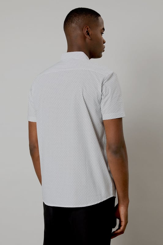 Crafted from pure cotton for exceptional comfort and breathability
        Subtle geo print pattern adds contemporary visual interest
        Classic collar and button-through front for a timeless silhouette
        Short sleeves designed for warm-weather versatility
        Regular fit provides ease of movement for all-day wear
    
    This Burton geo print shirt combines classic styling with modern detailing, perfect for the man who appreciates understated sophistication. The lightweight cotton construction makes it ideal for casual summer occasions, whilst the versatile design allows for effortless styling. Pair with dark trousers as shown for an evening at the pub with mates, or team with chino shorts for family barbecues and weekend outings. The clean lines and subtle pattern work equally well for casual Fridays at the office - simply add a lightweight blazer to sharpen the look. Easy to care for and comfortable to wear, this shirt represents the perfect balance of practicality and style that Burton is known for. A wardrobe essential that will serve you well throughout the warmer months.