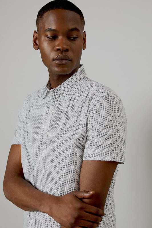 Crafted from pure cotton for exceptional comfort and breathability
        Subtle geo print pattern adds contemporary visual interest
        Classic collar and button-through front for a timeless silhouette
        Short sleeves designed for warm-weather versatility
        Regular fit provides ease of movement for all-day wear
    
    This Burton geo print shirt combines classic styling with modern detailing, perfect for the man who appreciates understated sophistication. The lightweight cotton construction makes it ideal for casual summer occasions, whilst the versatile design allows for effortless styling. Pair with dark trousers as shown for an evening at the pub with mates, or team with chino shorts for family barbecues and weekend outings. The clean lines and subtle pattern work equally well for casual Fridays at the office - simply add a lightweight blazer to sharpen the look. Easy to care for and comfortable to wear, this shirt represents the perfect balance of practicality and style that Burton is known for. A wardrobe essential that will serve you well throughout the warmer months.