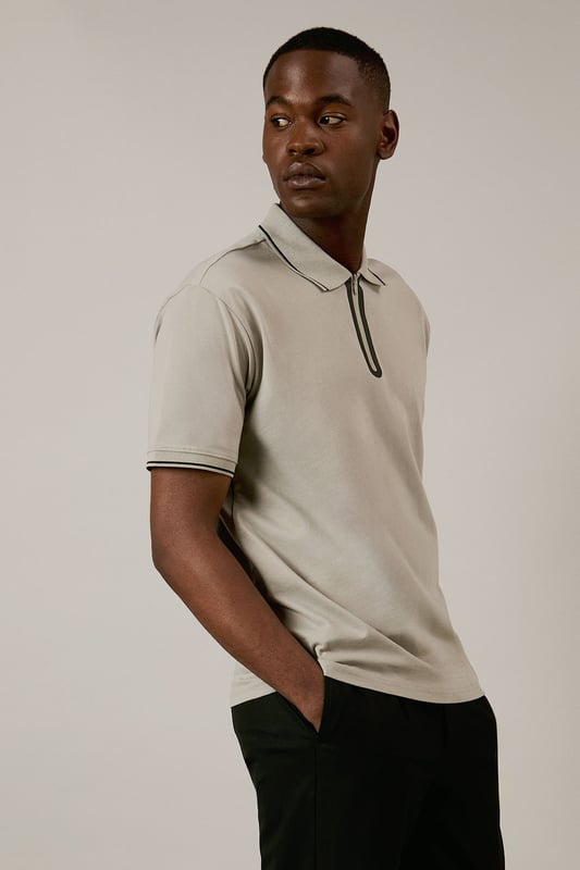 From Burton's exclusive 1904 Collection, featuring mercerised cotton for enhanced lustre and durability
        Quarter-zip neck design with contrast tipping detail along the collar and sleeves
        Classic polo silhouette with short sleeves for comfortable everyday wear
        Soft cotton fabric with a smooth, refined finish that maintains shape throughout the day
        Versatile design that transitions effortlessly from casual daywear to relaxed evening settings
    
    This 1904 Mercerised Zip Neck Polo represents Burton's commitment to timeless menswear with contemporary touches. The quarter-zip detail adds a distinctive element to the classic polo silhouette, whilst the mercerised finish gives the cotton a subtle sheen that distinguishes it from ordinary polos. Style with dark trousers and white trainers as shown for a smart-casual look perfect for weekend pub gatherings or family barbecues. For a more relaxed approach, pair with your favourite denim and canvas trainers. The clean lines and understated design make this polo an excellent choice for casual office environments or sporting events where you want to look put-together without appearing overdressed. A versatile wardrobe staple that works across seasons - layer under a lightweight jacket during cooler months or wear alone when temperatures rise.