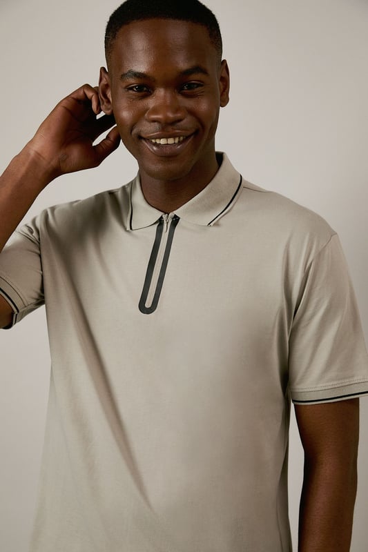 From Burton's exclusive 1904 Collection, featuring mercerised cotton for enhanced lustre and durability
        Quarter-zip neck design with contrast tipping detail along the collar and sleeves
        Classic polo silhouette with short sleeves for comfortable everyday wear
        Soft cotton fabric with a smooth, refined finish that maintains shape throughout the day
        Versatile design that transitions effortlessly from casual daywear to relaxed evening settings
    
    This 1904 Mercerised Zip Neck Polo represents Burton's commitment to timeless menswear with contemporary touches. The quarter-zip detail adds a distinctive element to the classic polo silhouette, whilst the mercerised finish gives the cotton a subtle sheen that distinguishes it from ordinary polos. Style with dark trousers and white trainers as shown for a smart-casual look perfect for weekend pub gatherings or family barbecues. For a more relaxed approach, pair with your favourite denim and canvas trainers. The clean lines and understated design make this polo an excellent choice for casual office environments or sporting events where you want to look put-together without appearing overdressed. A versatile wardrobe staple that works across seasons - layer under a lightweight jacket during cooler months or wear alone when temperatures rise.