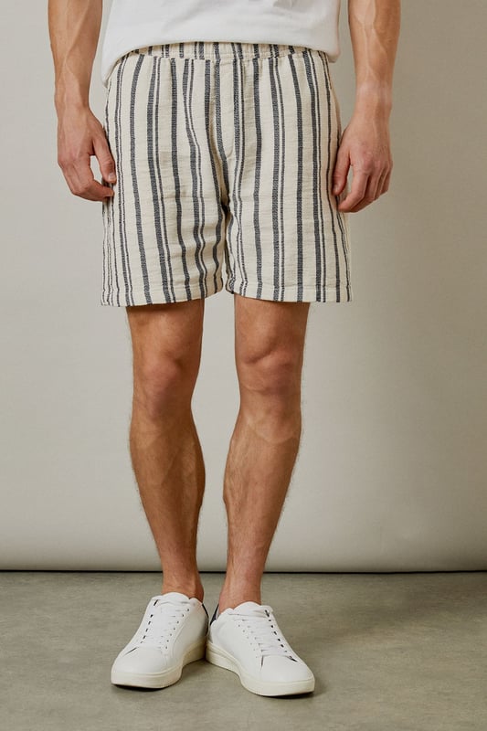 Textured woven fabric with vertical stripe pattern for a classic summer aesthetic
        Relaxed fit design offering optimal comfort for warm-weather wear
        Practical back pocket detail for essential storage
        Mid-thigh length cut for a contemporary casual look
        Versatile design that pairs effortlessly with both casual and smart-casual tops
    
    These Burton textured casual shorts deliver laid-back sophistication for the modern man who values both comfort and style. The distinctive vertical stripe pattern adds visual interest while maintaining versatility for numerous styling options. Pair with a crisp white t-shirt and trainers as shown for an effortless daytime look, or match with the coordinating shirt to create a fashionable co-ord set perfect for summer socials. The relaxed silhouette ensures unrestricted movement, making these shorts ideal for barbecues, casual pub outings with mates, or weekend getaways. The neutral tones allow for easy integration into your existing wardrobe, while the textured fabric adds a subtle touch of refinement. Machine washable at 30 degrees, these shorts combine practicality with enduring style for the discerning gentleman.