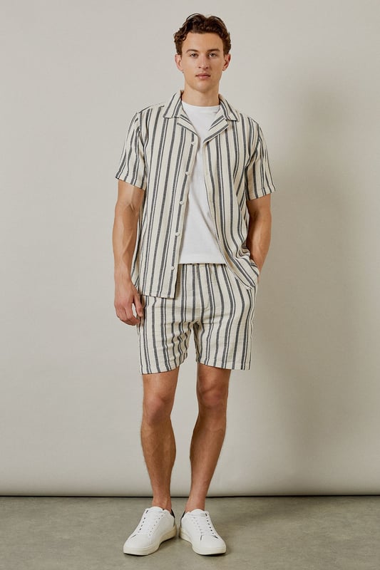 Textured woven fabric with vertical stripe pattern for a classic summer aesthetic
        Relaxed fit design offering optimal comfort for warm-weather wear
        Practical back pocket detail for essential storage
        Mid-thigh length cut for a contemporary casual look
        Versatile design that pairs effortlessly with both casual and smart-casual tops
    
    These Burton textured casual shorts deliver laid-back sophistication for the modern man who values both comfort and style. The distinctive vertical stripe pattern adds visual interest while maintaining versatility for numerous styling options. Pair with a crisp white t-shirt and trainers as shown for an effortless daytime look, or match with the coordinating shirt to create a fashionable co-ord set perfect for summer socials. The relaxed silhouette ensures unrestricted movement, making these shorts ideal for barbecues, casual pub outings with mates, or weekend getaways. The neutral tones allow for easy integration into your existing wardrobe, while the textured fabric adds a subtle touch of refinement. Machine washable at 30 degrees, these shorts combine practicality with enduring style for the discerning gentleman.
